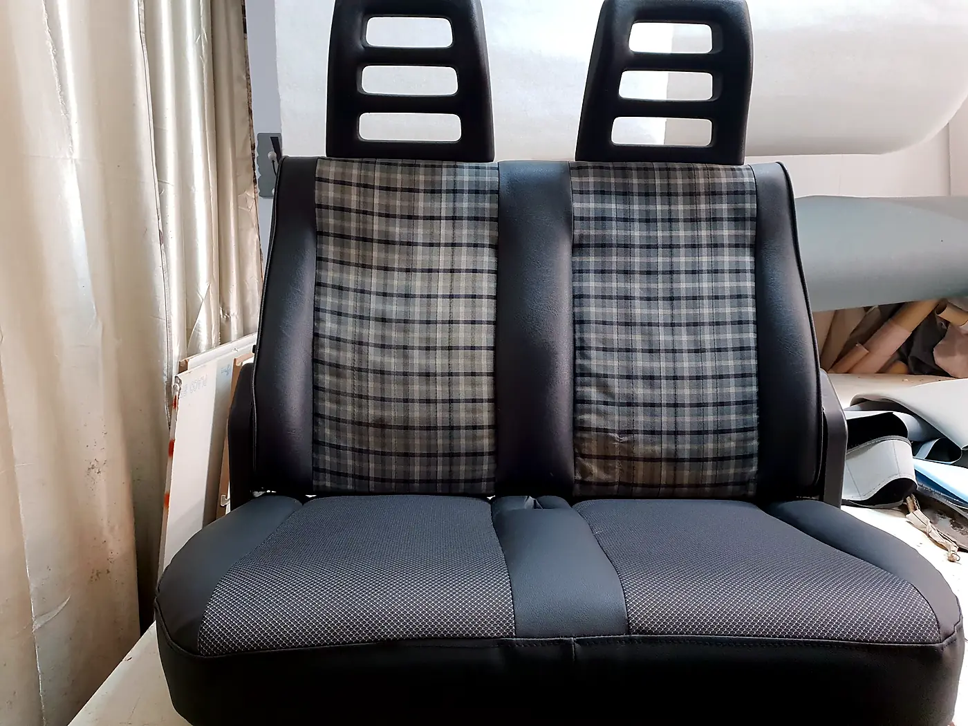 Asiento corrido de vehículo tapizado en negro y tela de cuadros