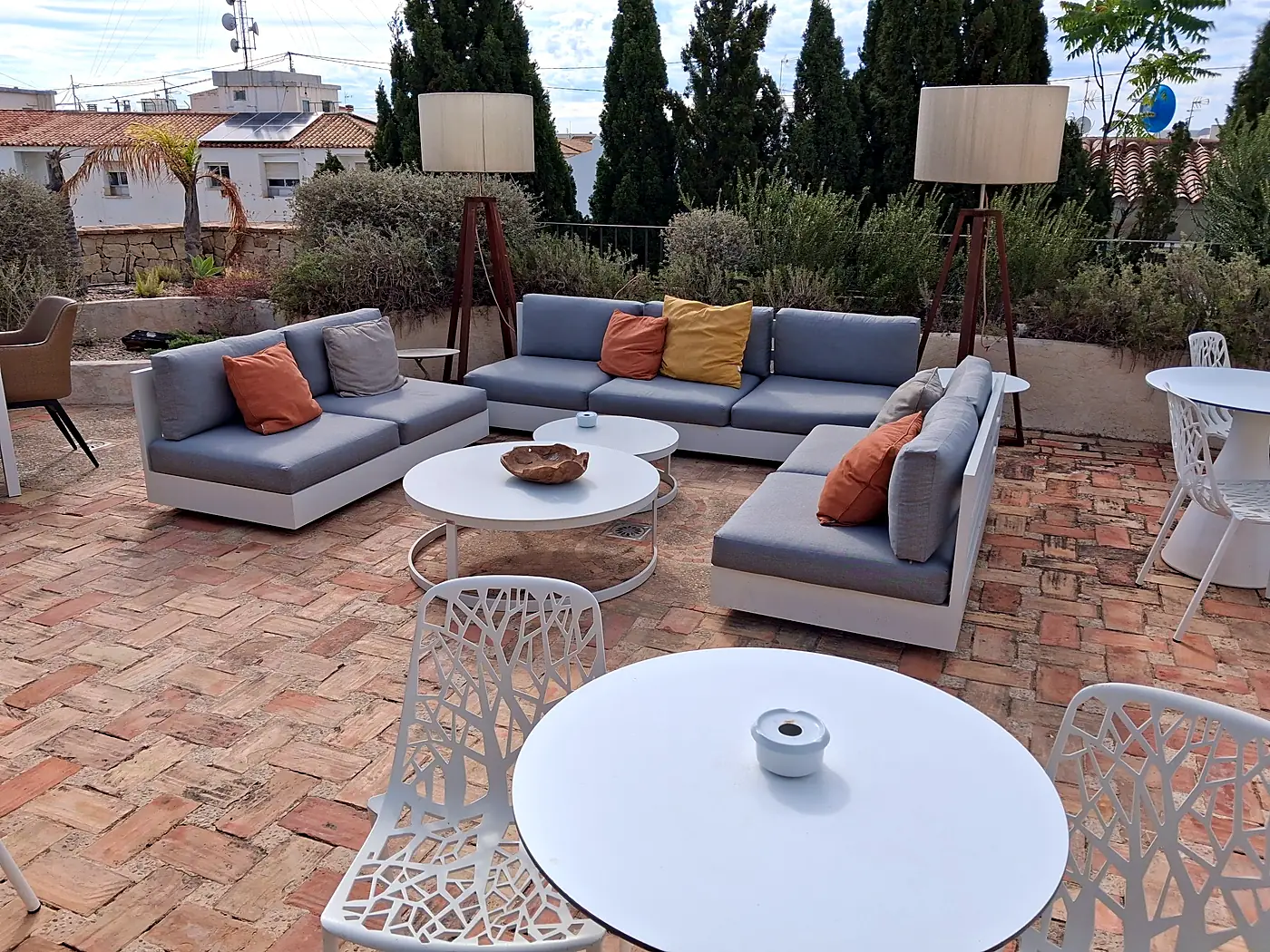 Sofás de exterior con cojines grises y naranjas en la terraza de un hotel