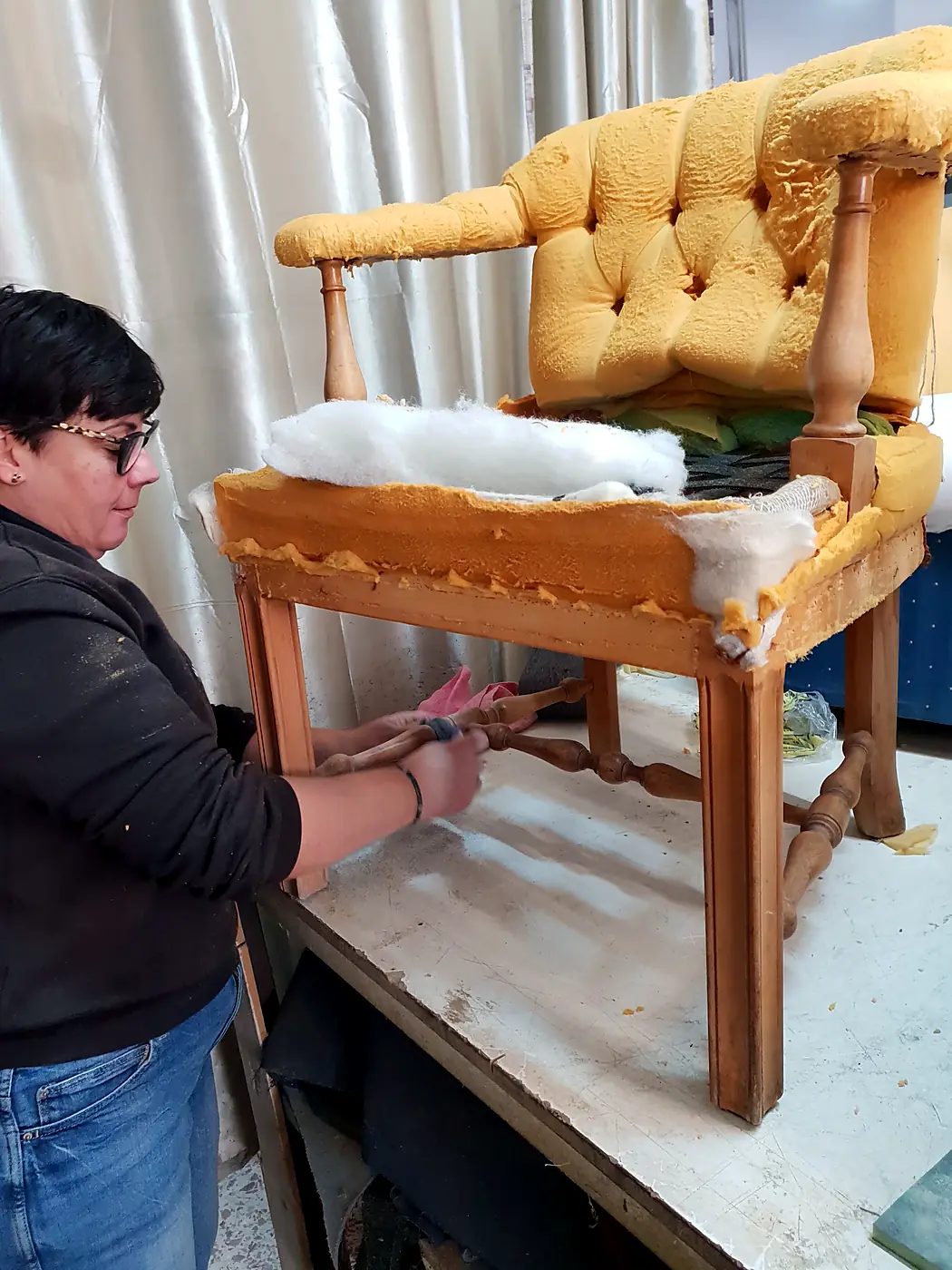 Tapicera trabajando en una butaca capitoné en el taller