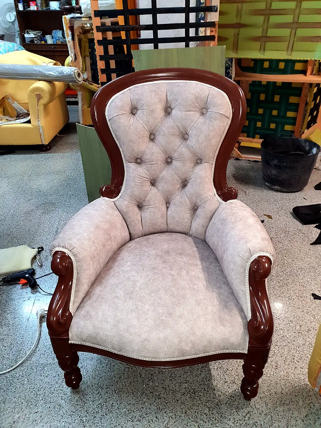 Carved wooden armchair with a grey buttoned back
