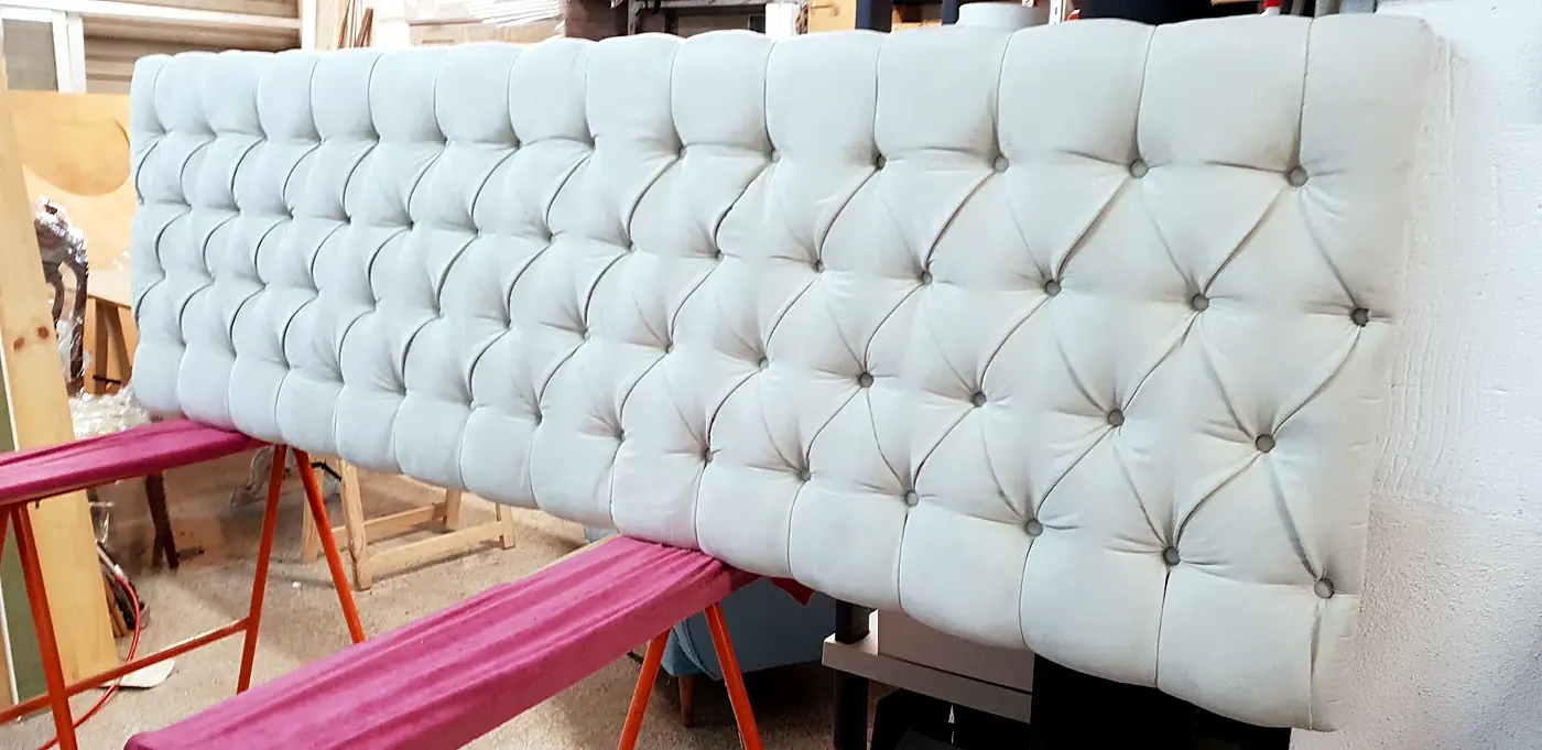 Headboard upholstered in white buttoned fabric