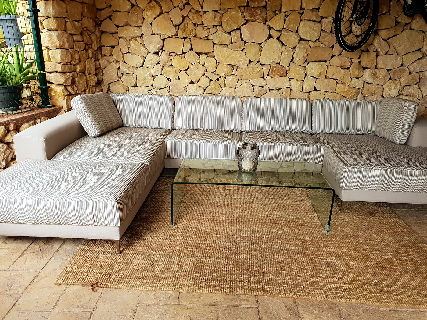 L-shaped sofa upholstered in light striped fabric in front of a stone wall